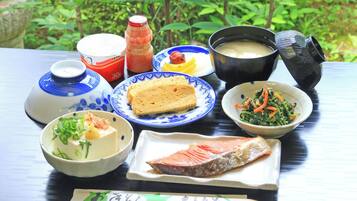 Une table dressée avec différents plats, notamment un bol de soupe, une assiette de poisson et un plat de légumes.