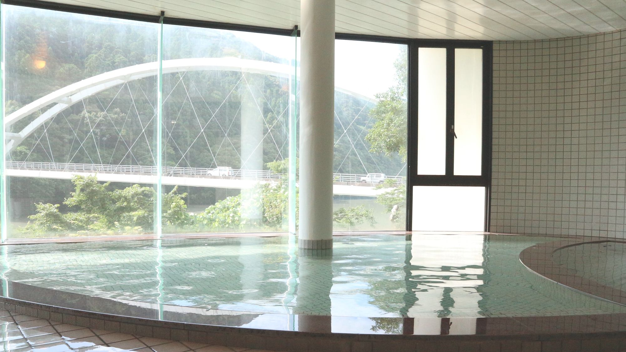 Una piscina interior con vistas a un puente y vegetación.