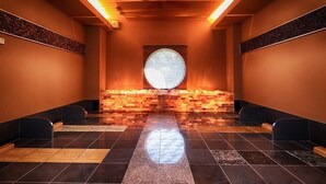 Un área de spa con un ventanal circular central, suelo de baldosas y bancos a lo largo de las paredes.