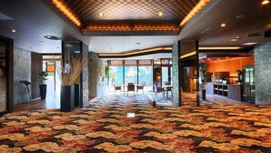 Un vestíbulo espacioso con alfombra estampada, techo a cuadros y vistas al comedor.