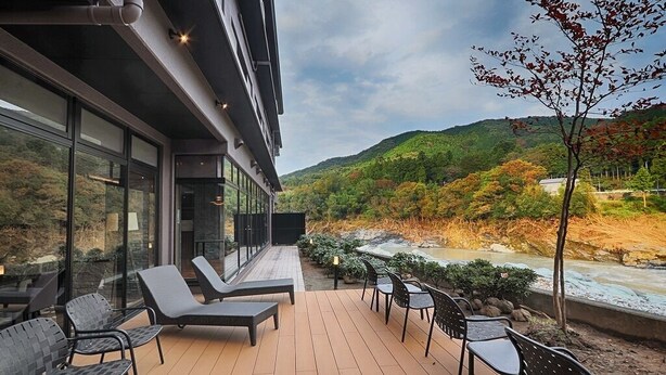 Una terraza con asientos al aire libre y vistas a un río y colinas.