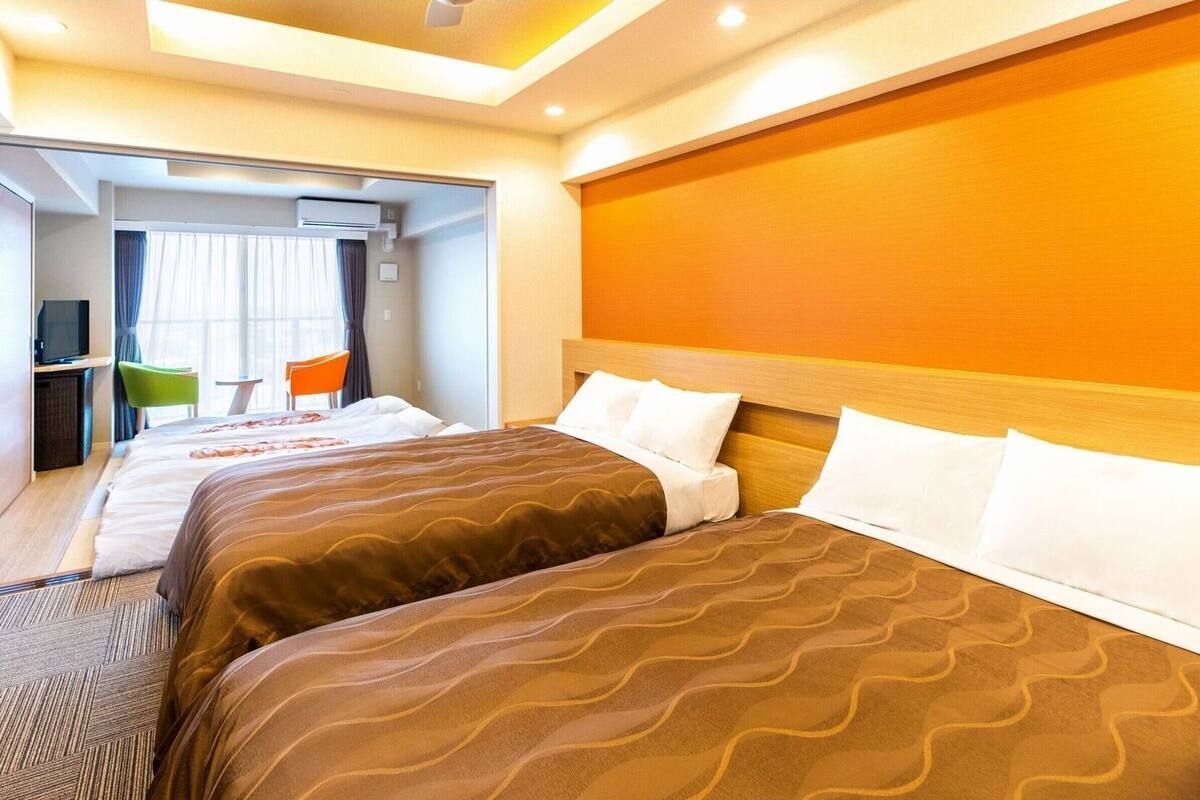 Une chambre d’hôtel avec deux lits, une télévision, un bureau et une chaise.