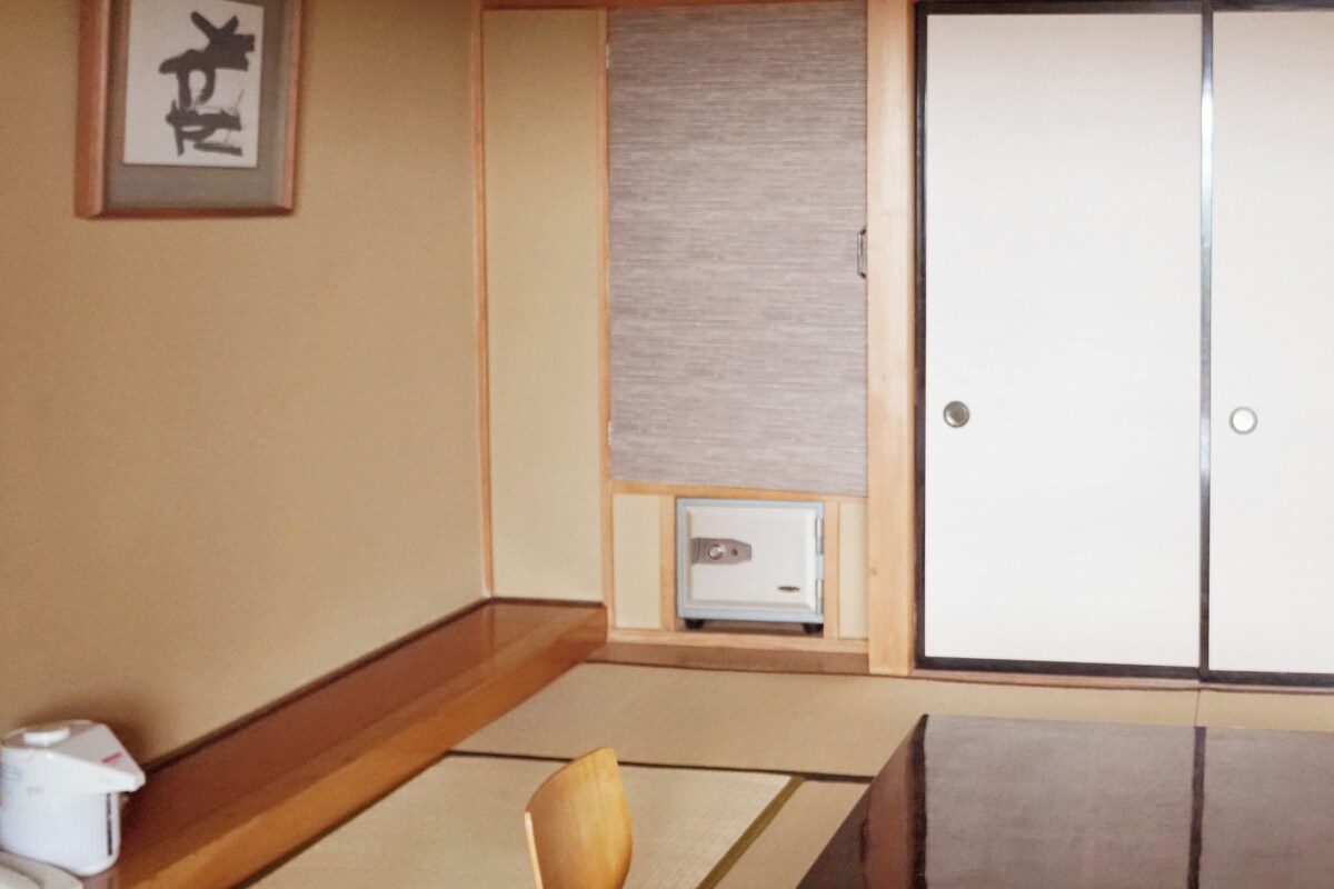 A traditional Japanese room with tatami flooring, a shoji screen, a wooden desk, and a sliding door.