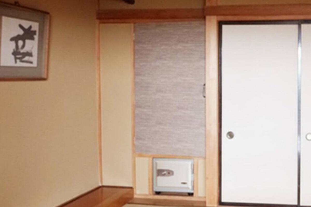 Una habitación con una puerta corredera, un cuadro en la pared y un pequeño armario.