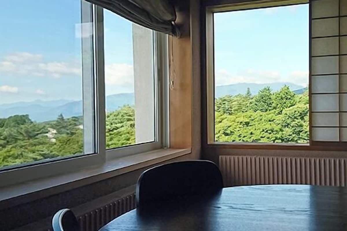 A room with a large window, a table, and a chair.