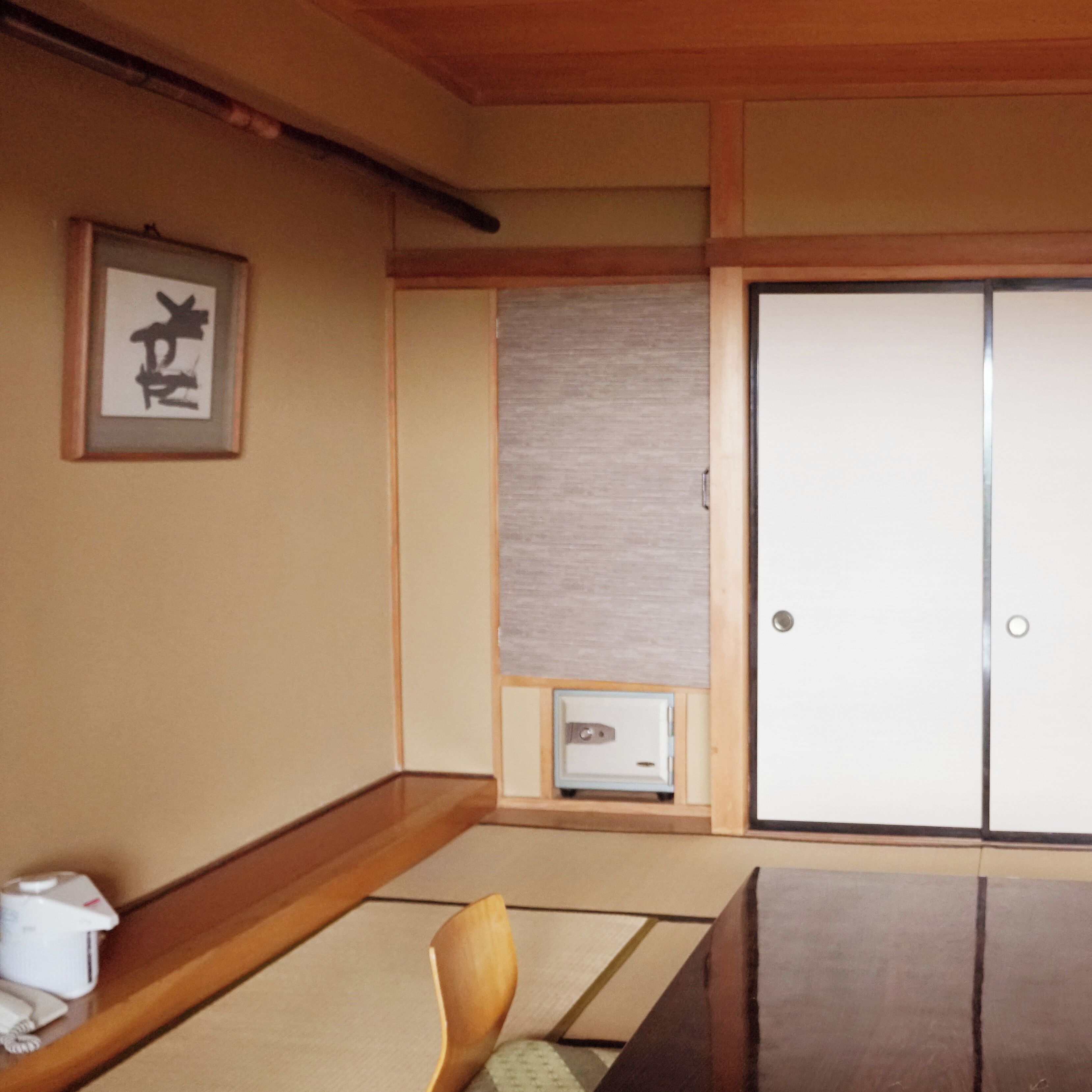 A traditional Japanese room with tatami flooring, a shoji screen, a wooden desk, and a sliding door.