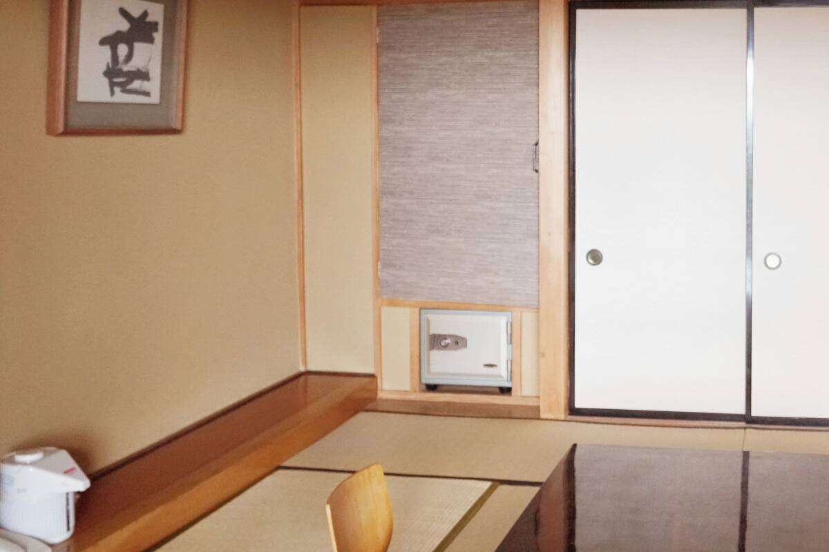 Una habitación tradicional japonesa con suelo de tatami, un panel shoji, un escritorio de madera y una puerta corredera.