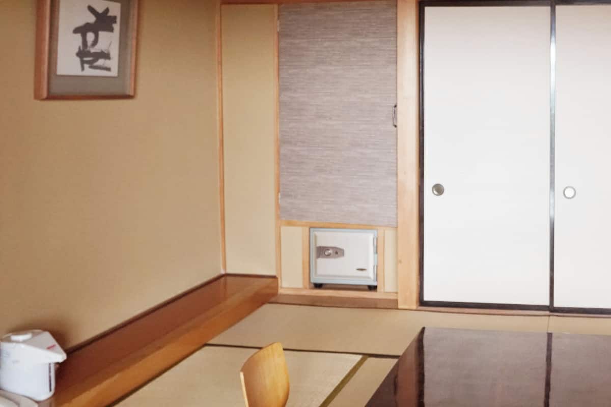 A traditional Japanese room with tatami flooring, a shoji screen, a wooden desk, and a sliding door.