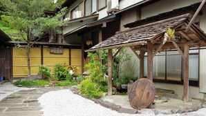 A traditional Japanese building with a wooden structure, a stone pathway, and various plants. - Ryokan Tsurutomiyashiki (Shiiba-son)