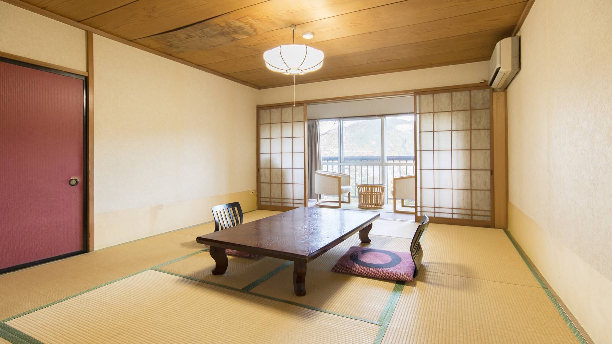 Une pièce de style japonais traditionnel, avec un sol recouvert de tatamis, une table basse, des chaises et une porte coulissante.