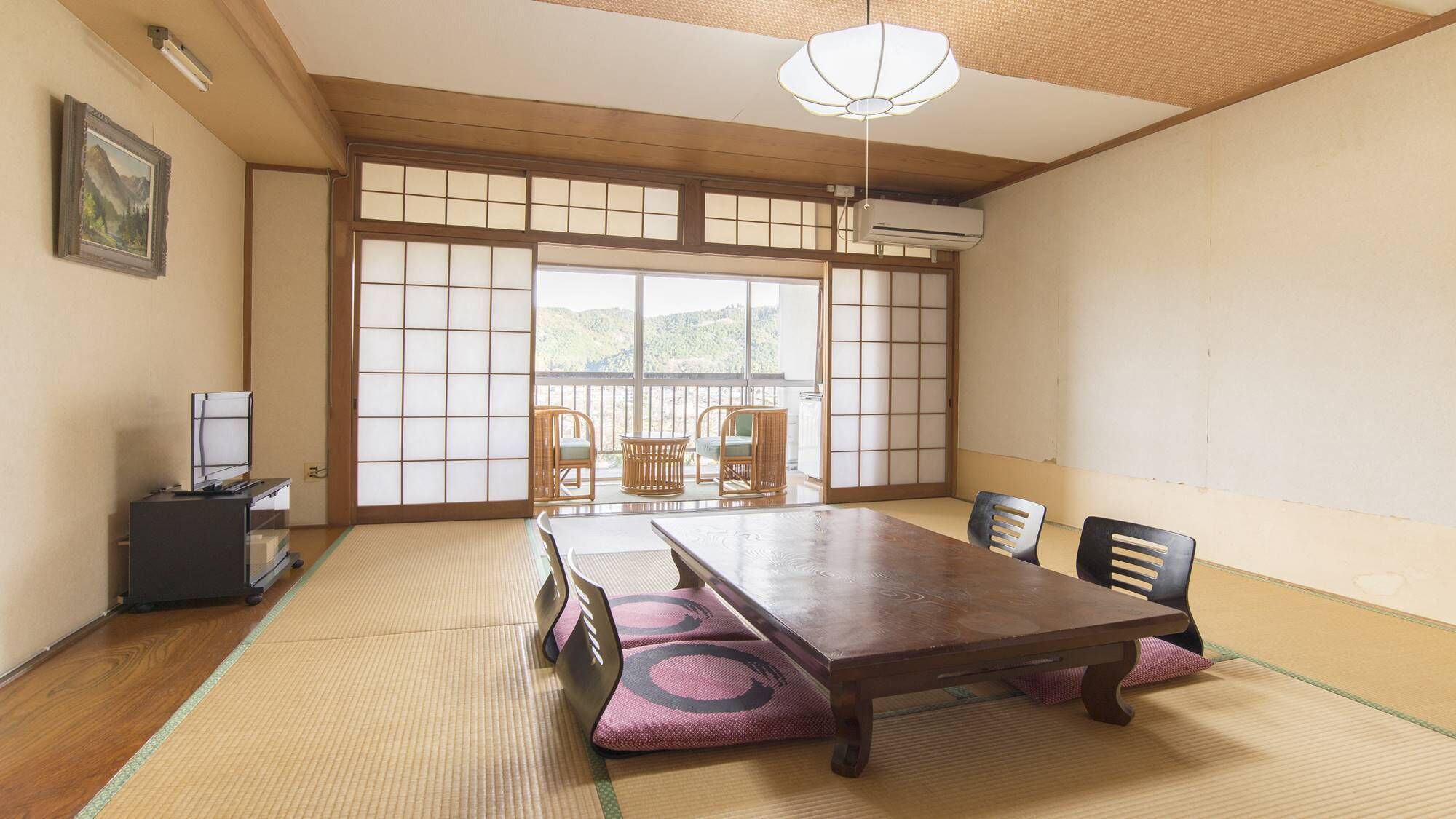 A traditional Japanese room with tatami flooring, a low table, chairs, and a sliding door with a view.