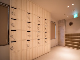 A hotel room with a large wooden wardrobe, a clock on the wall, and a staircase.