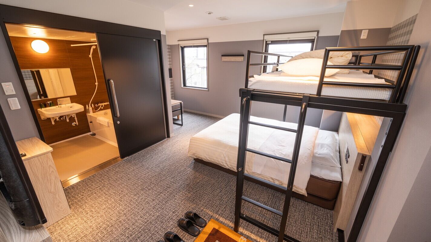 A bunk bed room with a bathroom and a desk.