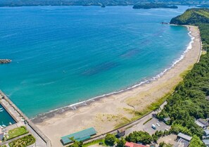 An aerial view of a coastal area with a beach, a road, and buildings.