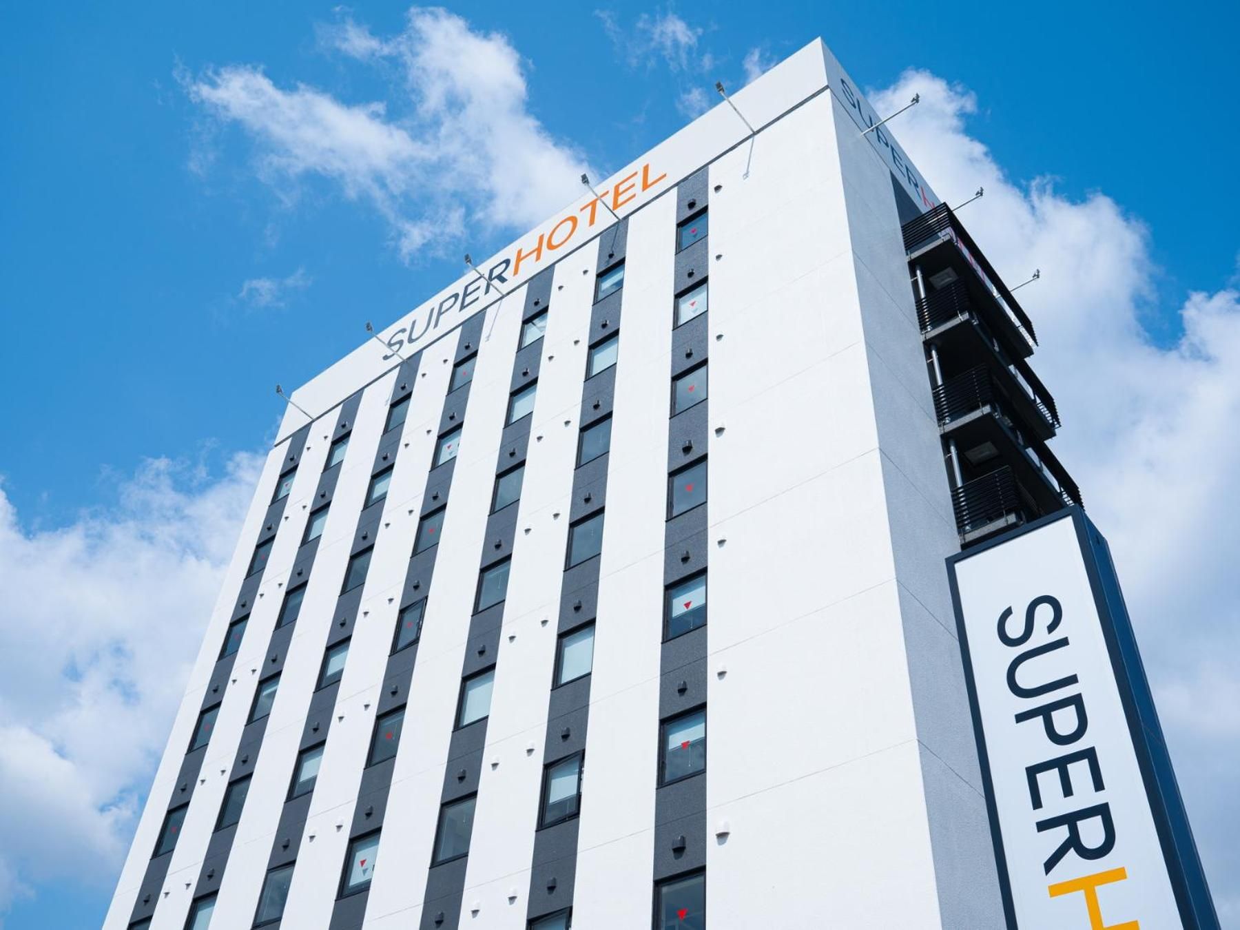 A tall hotel building with the name 'SUPERHOTEL' prominently displayed on the facade.