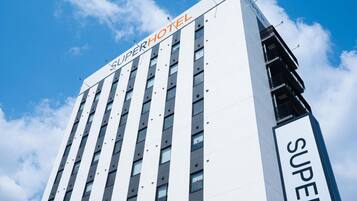 A tall hotel building with the name 'SUPERHOTEL' prominently displayed on the facade.