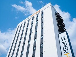 A tall hotel building with the name 'SUPERHOTEL' prominently displayed on the facade.