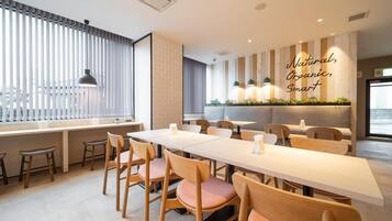 A modern dining area with a long table, wooden chairs, and a wall with a vertical garden.