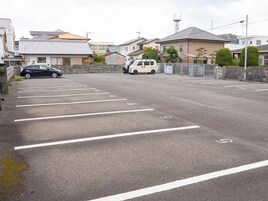 A parking lot with marked spaces, a black car, and a white van.