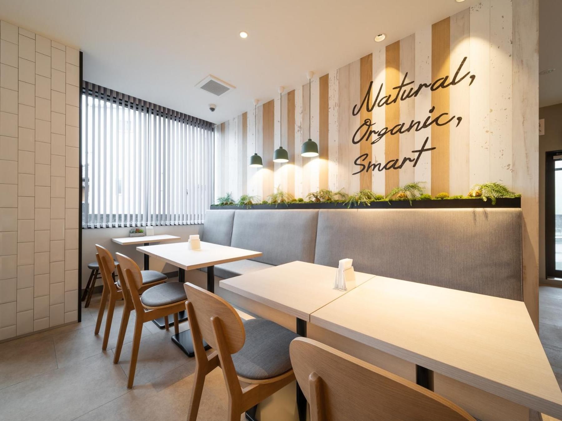 Een modern restaurantinterieur met een lange toonbank, houten stoelen en een wand met verticale houten latten.