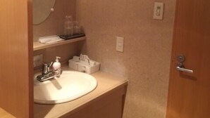 A small bathroom with a round mirror, a sink, and a wooden door. - Well Goshikihama Resort Center (Sumoto)