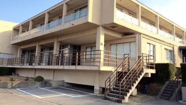 A multi-story building with balconies, a parking area, and a staircase. - Well Goshikihama Resort Center (Sumoto)