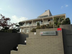 A modern building with a flat roof and a sign indicating it is a Well Group property. - Well Goshikihama Resort Center (Sumoto)