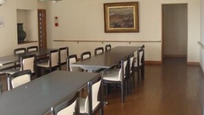 A dining area with multiple tables and chairs, a painting on the wall, and a ceiling light fixture. - Well Goshikihama Resort Center (Sumoto)