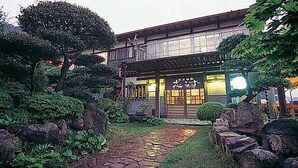 Un edificio tradicional japonés con un camino de piedra que lleva a la entrada.
