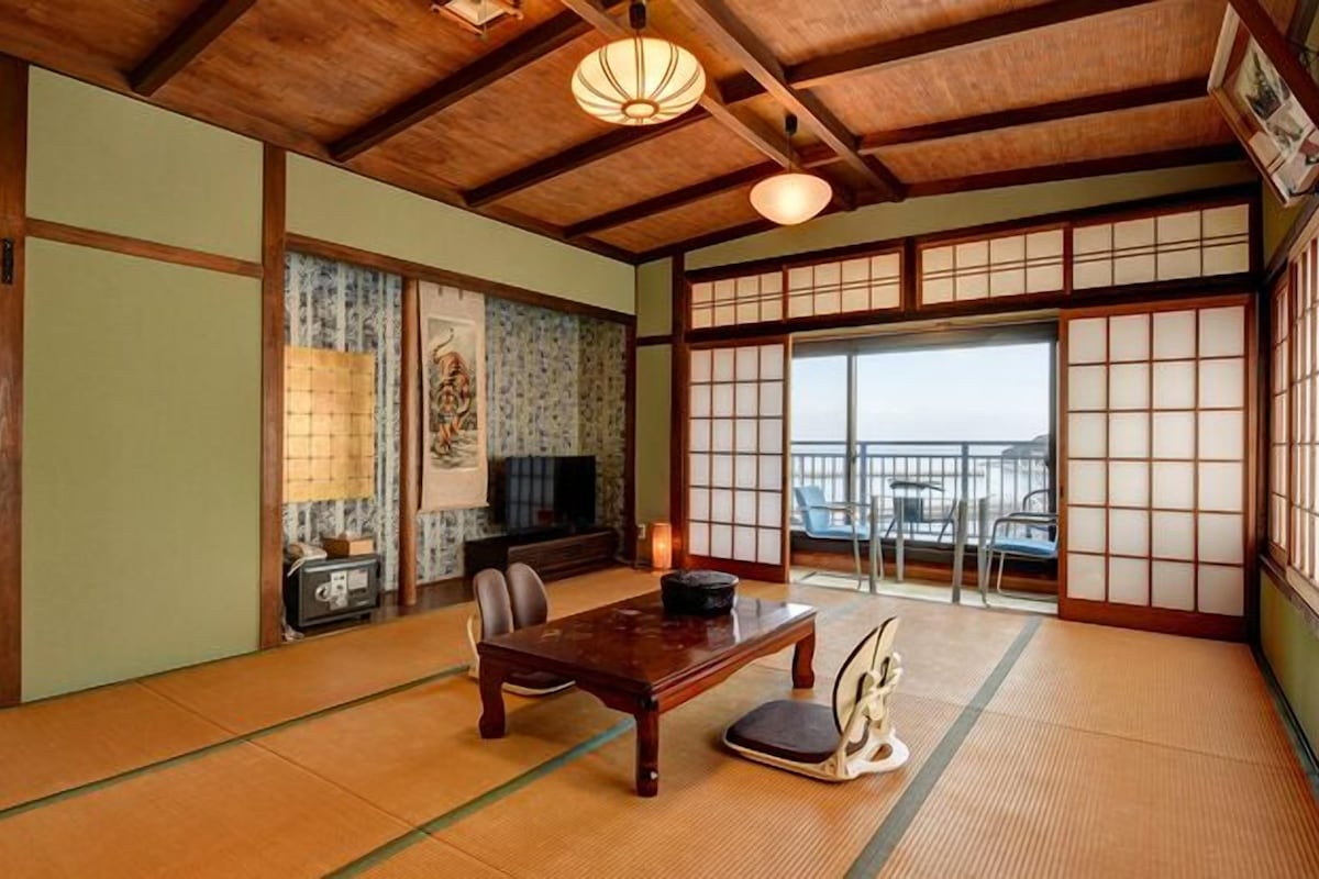 Um quarto japonês tradicional com tatames, uma mesa baixa e portas deslizantes.