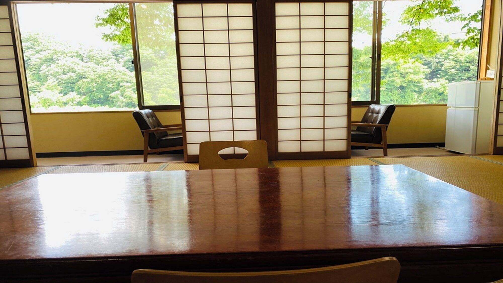A traditional Japanese room with tatami flooring, a low table, and sliding doors.