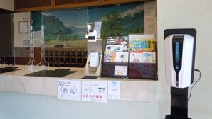 A reception area with a counter, a digital thermometer, and various informational posters. - Sunrise Hotel (Ryugasaki)