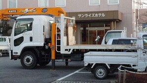 A white truck with a flatbed trailer parked in front of a building with a sign in Japanese. - Sunrise Hotel (Ryugasaki)