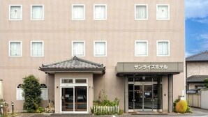 A multi-story hotel with a flat facade, a central entrance with a tiled roof, and a sign in Japanese. - Sunrise Hotel (Ryugasaki)