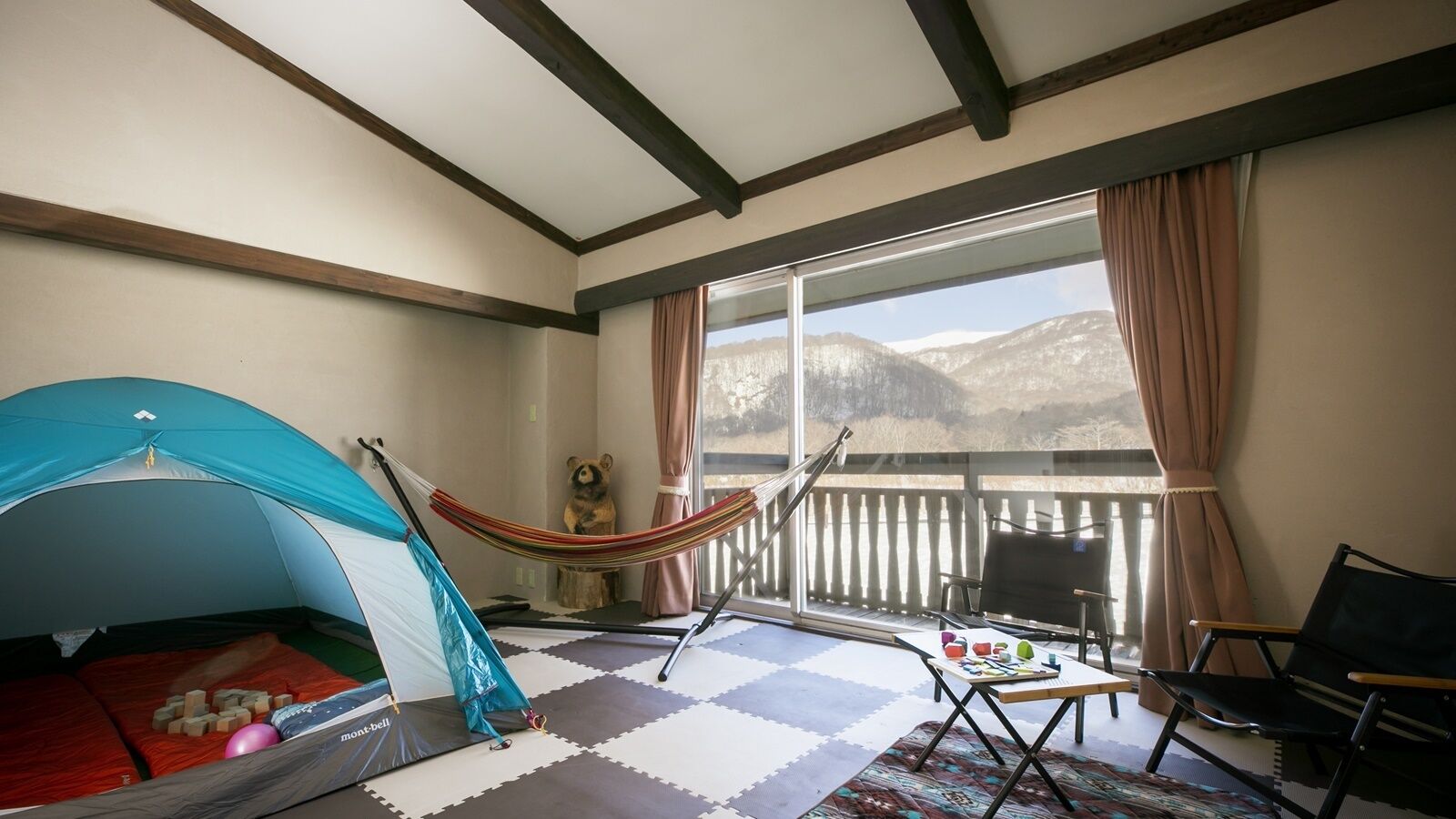 A room with a tent, hammock, and a view of mountains.