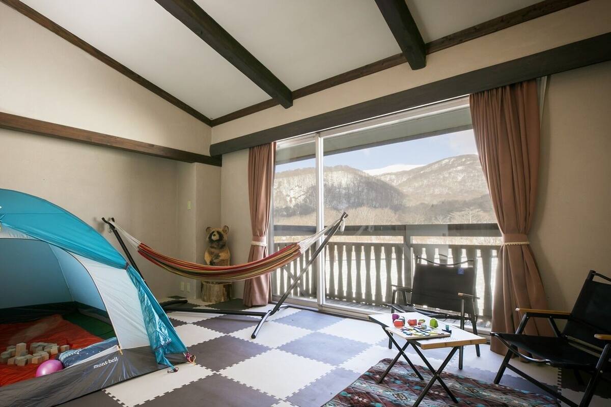 Ein Zimmer mit Zelt, Hängematte und Bergblick.