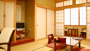 A traditional Japanese room with tatami flooring, a low table with a red mat, a television, and a shoji screen door. - Echigoya Ryokan <miyagiken> (Osaki)