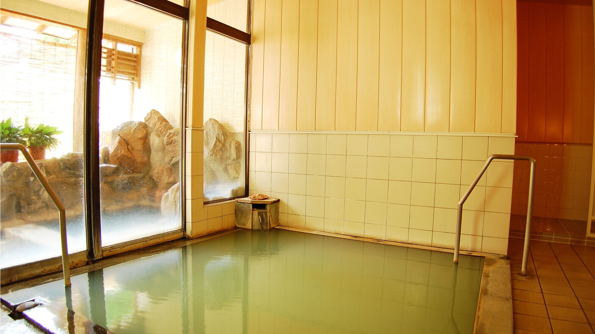 Un bain thermal avec un mur en pierre et un petit tabouret.