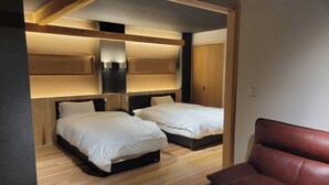 Une chambre d’hôtel moderne avec deux lits, un plafond en bois et un fauteuil en cuir.