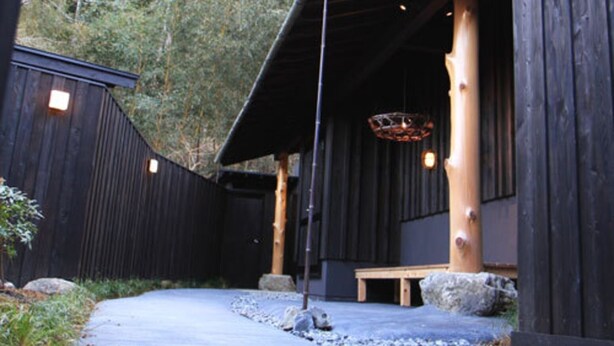 Un bâtiment traditionnel en bois, doté d’un toit à pente, d’un banc en bois et d’un chemin pavé de pierres.