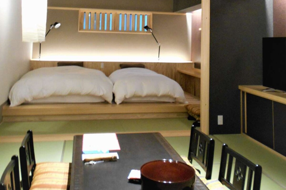 A compact room with a bed, a dining table, and chairs.