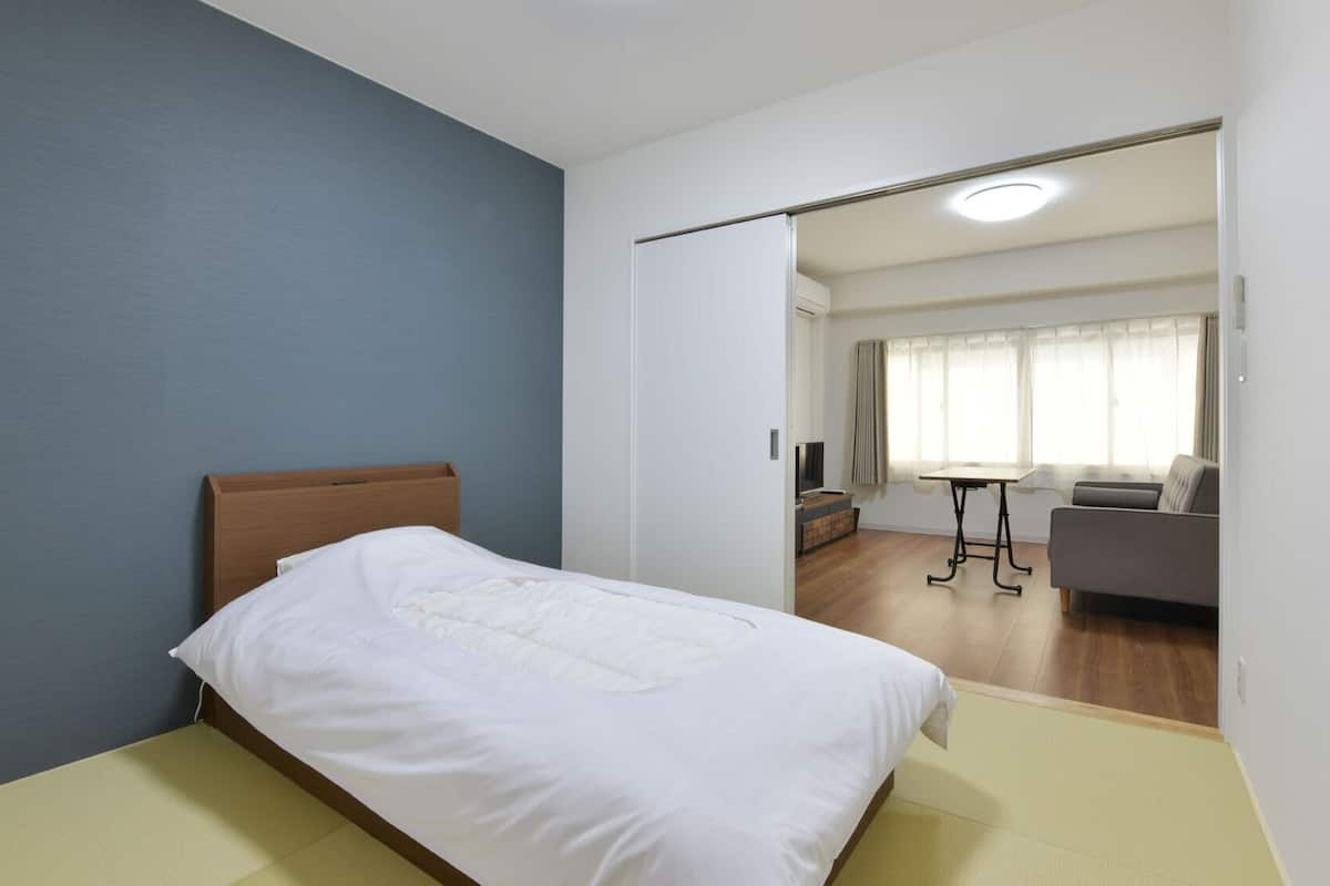 Ein Schlafzimmer mit einem Bett, einem Schreibtisch und einem Sofa im angrenzenden Raum.