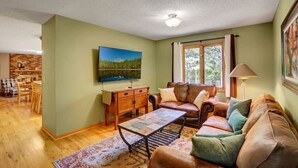 Un salon chaleureux avec une table basse en bois, un canapé en cuir et un téléviseur fixé au mur.
