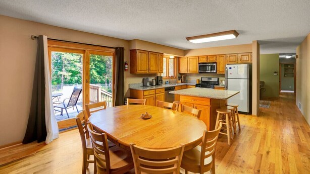 Une cuisine dotée de meubles en bois, d’un îlot central et d’un coin repas avec une table ronde et des chaises.