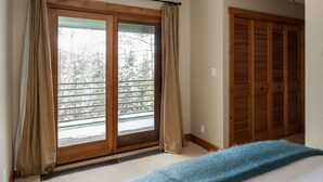 A room with a sliding glass door leading to a balcony, a wooden closet, and a ceiling light fixture. - Outpost: Windflower 2115 - Mountain Views! (Wilson)