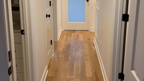 A hallway with wooden flooring, white walls, and a door with frosted glass. - Farmhouse Retreat (Rougemont)