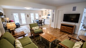 A living room with green sofas, a wooden coffee table, and a television. - Farmhouse Retreat (Rougemont)