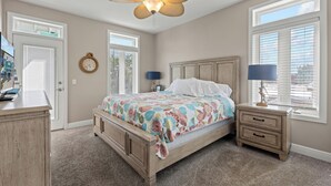 A bedroom with a bed, a nightstand, a dresser, a ceiling fan, and a window with blinds.