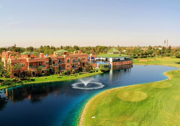 A resort with a large pool, a golf course, and a building with multiple balconies.