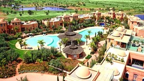 Un complexe hôtelier comprenant plusieurs bâtiments, une grande piscine et de vastes espaces verts environnants.